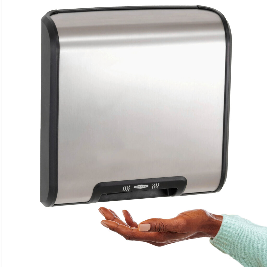 A woman’s hand reaches under a Bobrick TrimDry™ Surface-Mounted Automatic Hand Dryer.