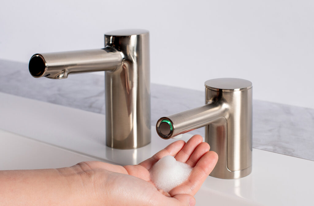 Foaming soap from a touch-free dispenser lands in a person’s open hand.